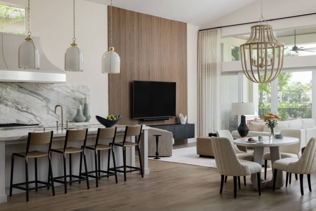 Modern open-concept home featuring a marble kitchen island, slatted wood TV accent wall, and a bright dining area designed by Piper Gonzalez Designs.